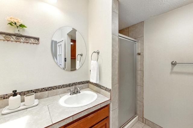 bathroom with a shower stall, vanity, tile patterned flooring, and a textured ceiling