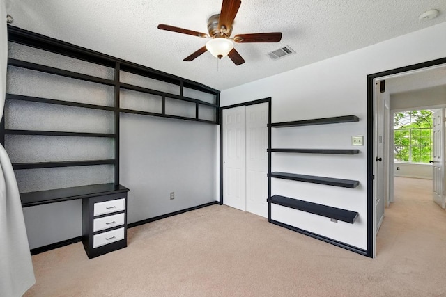 unfurnished bedroom with carpet, baseboards, a textured ceiling, a closet, and a ceiling fan