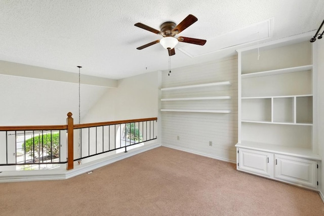 unfurnished room featuring attic access, a ceiling fan, light colored carpet, a textured ceiling, and vaulted ceiling