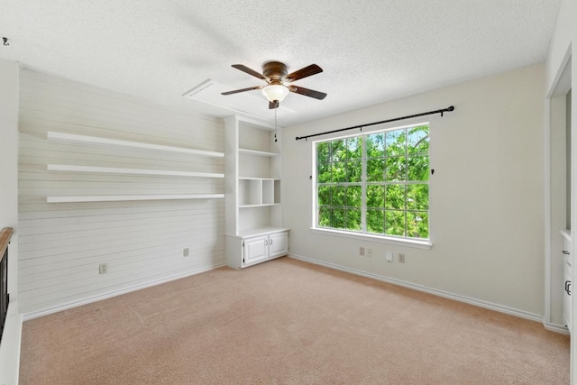 unfurnished bedroom with light carpet, a textured ceiling, baseboards, and a ceiling fan