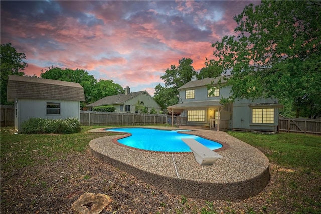 view of swimming pool featuring a diving board, an outbuilding, a storage shed, and a patio