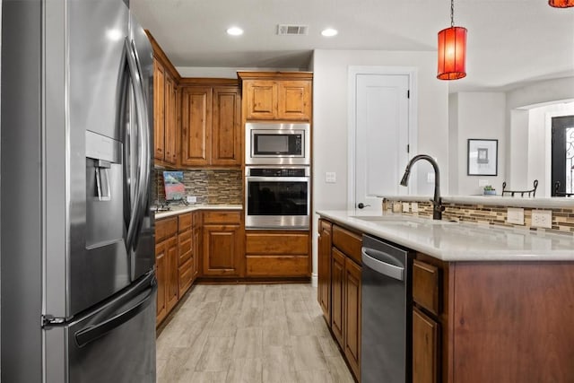905 Indian Hawthorne Dr Unit G, Georgetown, TX 78628 - kitchen with appliances with stainless steel finishes, a sink, decorative backsplash, brown cabinetry, and recessed lighting
