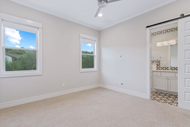 1107 Challenger, Lakeway, TX 78734 - unfurnished bedroom featuring light colored carpet, a barn door, ornamental molding, ensuite bath, and a ceiling fan