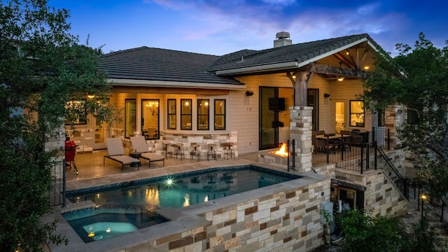 1107 Challenger, Lakeway, TX 78734 - back of house at dusk featuring a patio area, a fire pit, a chimney, and a tile roof
