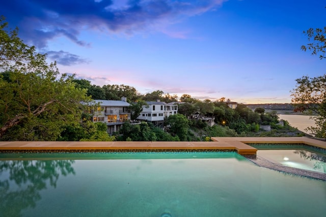 1107 Challenger, Lakeway, TX 78734 - pool at dusk featuring an outdoor pool and an in-ground hot tub