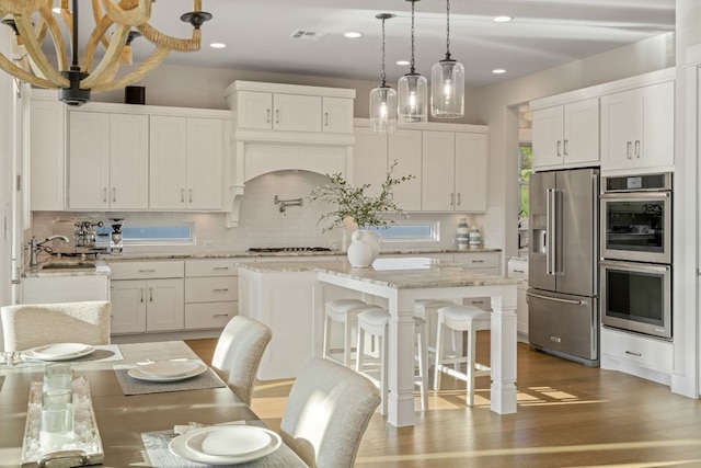 1107 Challenger, Lakeway, TX 78734 - kitchen with stainless steel appliances, decorative backsplash, white cabinetry, wood finished floors, and a center island