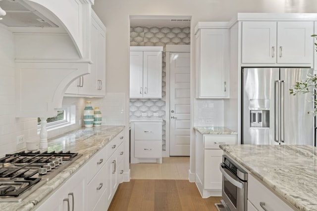 1107 Challenger, Lakeway, TX 78734 - kitchen featuring stainless steel appliances, white cabinets, light stone countertops, and light wood-style floors