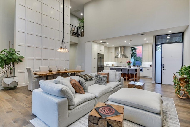 2010 Goodrich Ave Unit 5A, Austin, TX 78704 - living room with light wood-style flooring, a chandelier, a towering ceiling, and recessed lighting