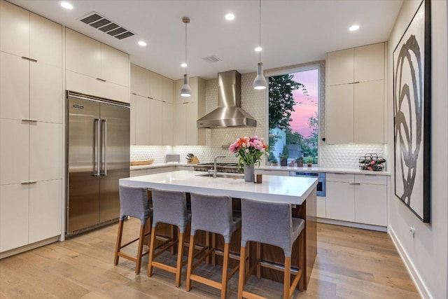 2010 Goodrich Ave Unit 5A, Austin, TX 78704 - kitchen featuring stainless steel built in fridge, wall chimney exhaust hood, tasteful backsplash, a breakfast bar, and light countertops