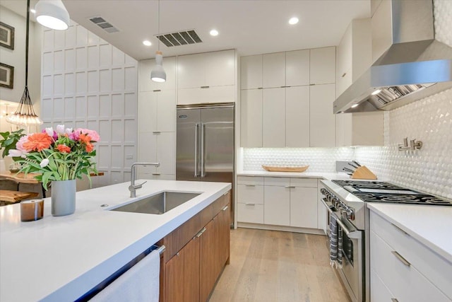 2010 Goodrich Ave Unit 5A, Austin, TX 78704 - kitchen featuring wall chimney range hood, high quality appliances, a sink, light wood-style floors, and light countertops