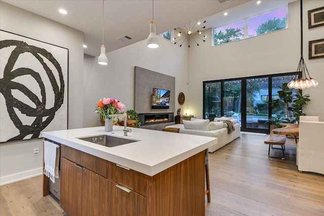 2010 Goodrich Ave Unit 5A, Austin, TX 78704 - kitchen with a sink, an island with sink, a glass covered fireplace, light wood finished floors, and a high ceiling