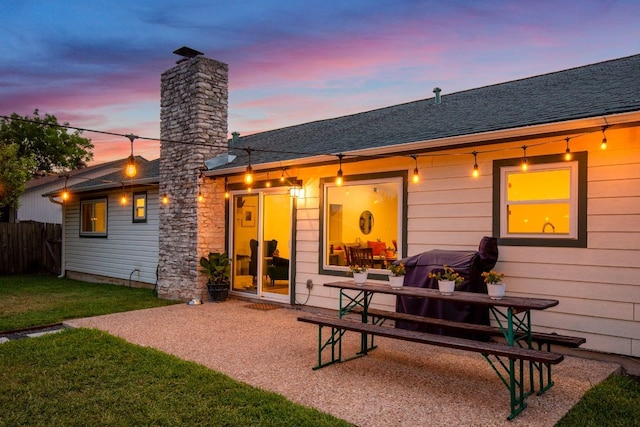 8907 Hunters Trce, Austin, TX 78758 - back of property at dusk featuring a chimney, a patio, and a shingled roof