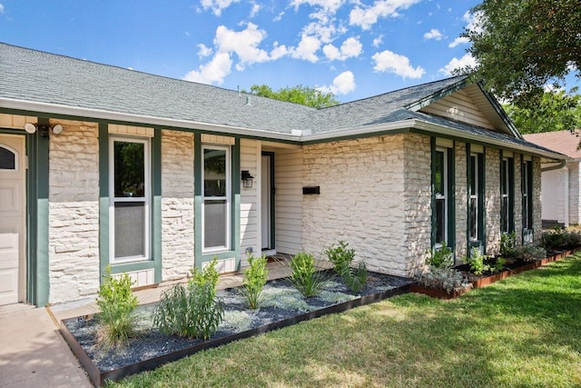 8907 Hunters Trce, Austin, TX 78758 - view of exterior entry featuring stone siding, a yard, and a shingled roof