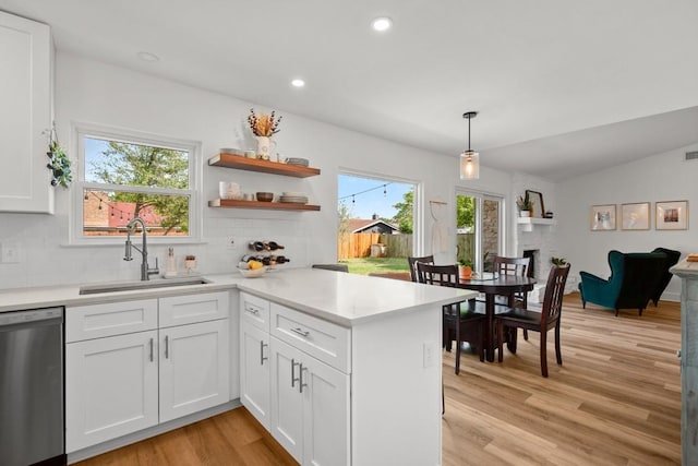 8907 Hunters Trce, Austin, TX 78758 - kitchen featuring stainless steel dishwasher, white cabinets, light wood-type flooring, a peninsula, and tasteful backsplash
