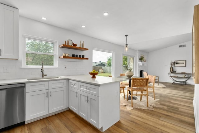 8907 Hunters Trce, Austin, TX 78758 - kitchen featuring dishwasher, light wood finished floors, light countertops, backsplash, and a peninsula