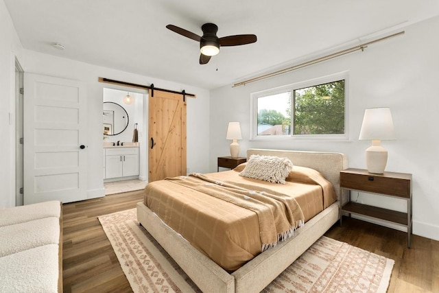 8907 Hunters Trce, Austin, TX 78758 - bedroom featuring a barn door, wood finished floors, connected bathroom, and ceiling fan
