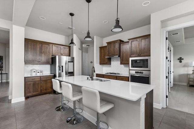 138 Prism Cv, Dripping Springs, TX 78620 - kitchen featuring a sink, tasteful backsplash, appliances with stainless steel finishes, light countertops, and a breakfast bar
