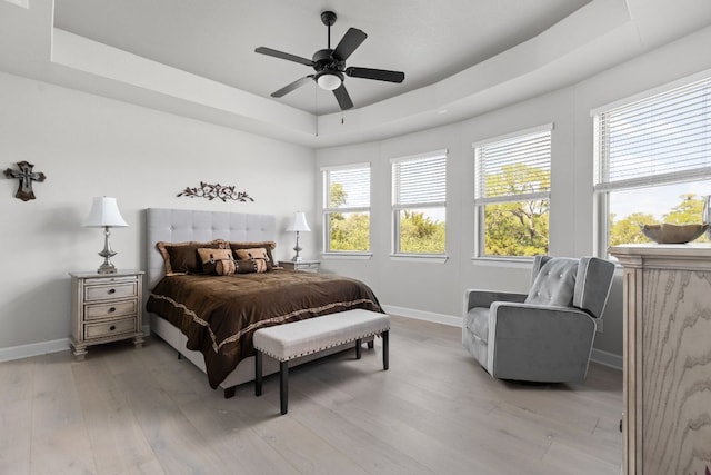 138 Prism Cv, Dripping Springs, TX 78620 - bedroom featuring baseboards, a raised ceiling, light wood finished floors, and a ceiling fan