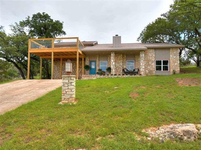 109 Ridgeview, Horseshoe Bay, TX 78657 - view of front of property featuring stone siding, a chimney, a front lawn, a wooden deck, and a carport