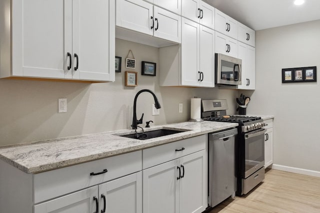 10730 N Platt River Dr, Austin, TX 78748 - kitchen featuring appliances with stainless steel finishes, a sink, light wood-style floors, baseboards, and light stone countertops