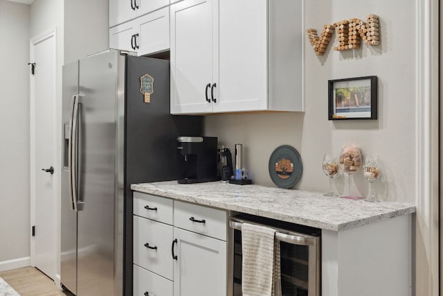 10730 N Platt River Dr, Austin, TX 78748 - kitchen featuring beverage cooler, white cabinetry, light wood finished floors, and light stone counters