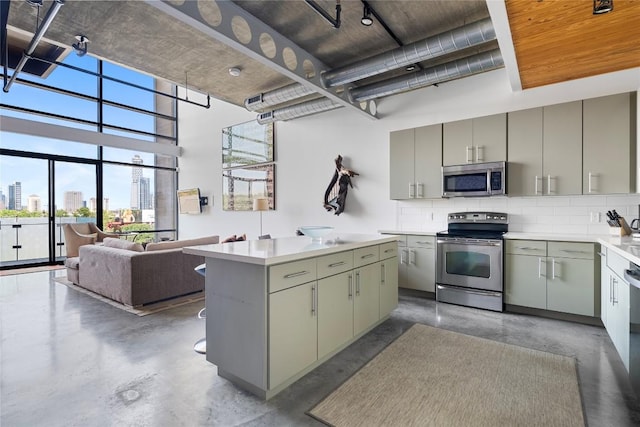 1401 Eva St Unit 406, Austin, TX 78704 - kitchen with stainless steel appliances, gray cabinetry, finished concrete floors, decorative backsplash, and a towering ceiling
