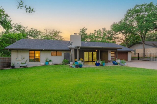 9421 Spring Hollow Dr, Austin, TX 78750 - back of house at dusk with a chimney, driveway, and a garage