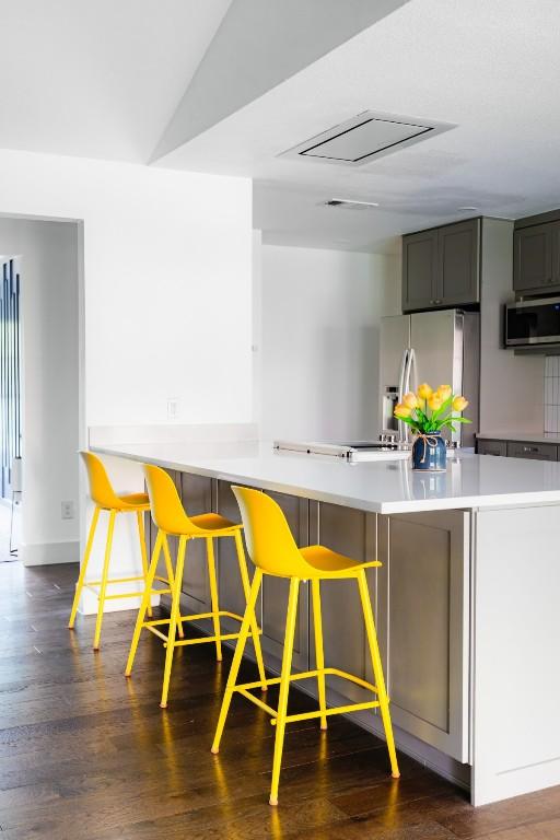 9421 Spring Hollow Dr, Austin, TX 78750 - kitchen with appliances with stainless steel finishes, dark wood-style floors, light countertops, and a breakfast bar