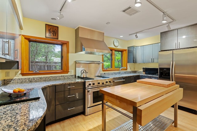 2507 Inwood Pl, Austin, TX 78703 - kitchen featuring rail lighting, appliances with stainless steel finishes, island exhaust hood, and light wood-type flooring