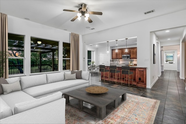 living area with ceiling fan, plenty of natural light, baseboards, and recessed lighting