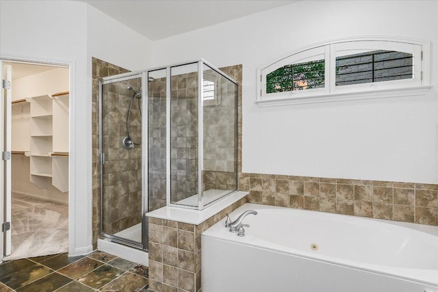 bathroom featuring a stall shower, a garden tub, and a walk in closet