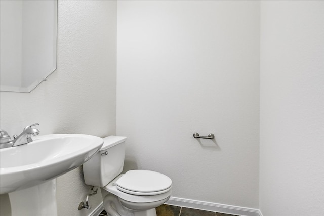 half bathroom with toilet, tile patterned flooring, a sink, and baseboards