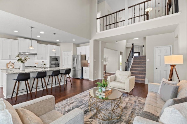 433 Vista Portola Loop, Liberty Hill, TX 78642 - living room featuring dark wood-type flooring, stairs, a towering ceiling, baseboards, and recessed lighting