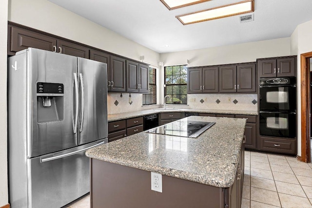 9002 Scotsman Dr, Austin, TX 78750 - kitchen with black appliances, tasteful backsplash, light stone counters, and a kitchen island