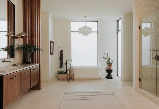 full bathroom with a shower stall, a freestanding bath, vanity, and tile patterned flooring