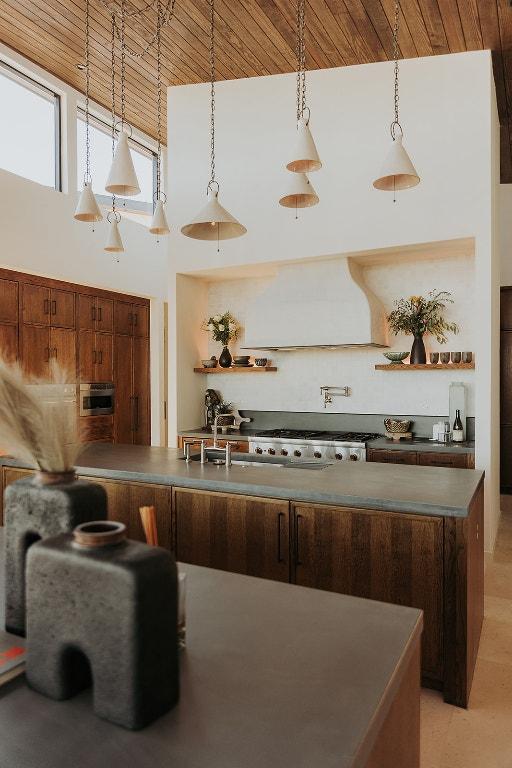 kitchen featuring range hood, open shelves, dark countertops, a high ceiling, and stove