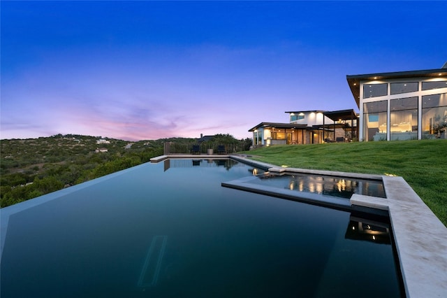 pool at dusk featuring a yard