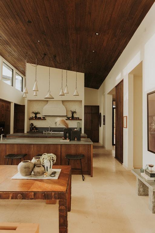 kitchen featuring wood ceiling, custom range hood, hanging light fixtures, a sink, and a breakfast bar