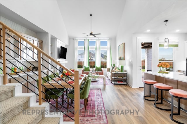 living room with a ceiling fan, light wood-style flooring, recessed lighting, stairway, and high vaulted ceiling