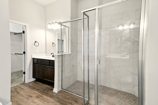 bathroom with wood finished floors, a shower stall, vanity, and a spacious closet