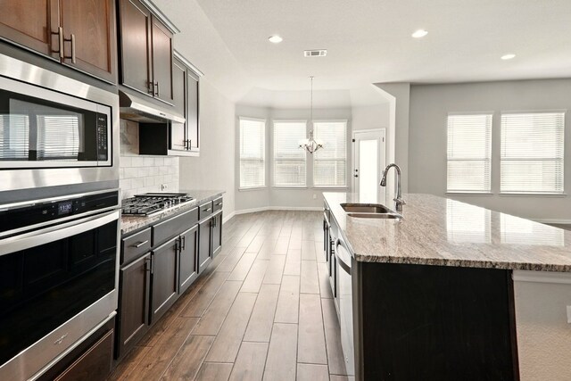 2300 La Mirada St, Leander, TX 78641 - kitchen with a sink, stainless steel appliances, wood finished floors, light stone counters, and under cabinet range hood