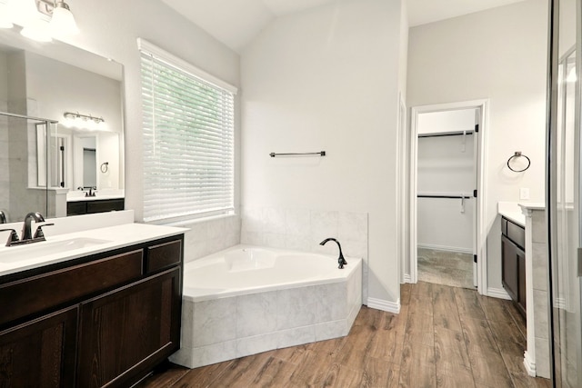 bathroom featuring a shower stall, vaulted ceiling, healthy amount of natural light, wood finished floors, and a garden tub