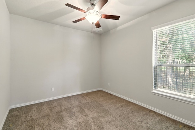 carpeted empty room with a ceiling fan and baseboards