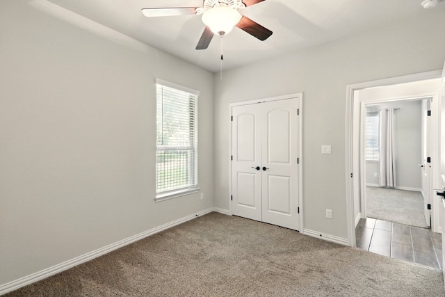 unfurnished bedroom with carpet flooring, baseboards, ceiling fan, and a closet