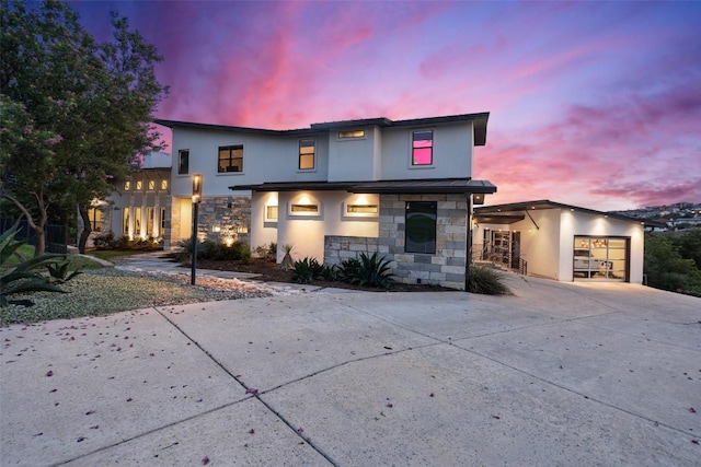 contemporary home with stucco siding, stone siding, concrete driveway, and a garage