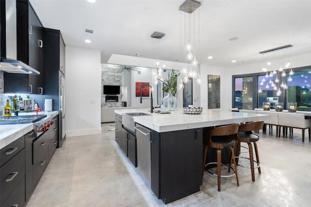 kitchen with wall chimney exhaust hood, a sink, finished concrete floors, dark cabinetry, and open floor plan