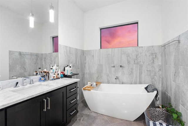 bathroom featuring tile walls, vanity, and a freestanding tub