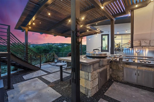 patio terrace at dusk with exterior kitchen and a grill