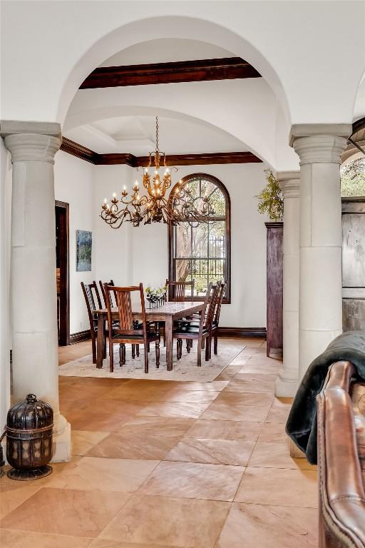 1710 Mount Larson Rd, Austin, TX 78746 - dining area featuring decorative columns, a chandelier, crown molding, arched walkways, and baseboards