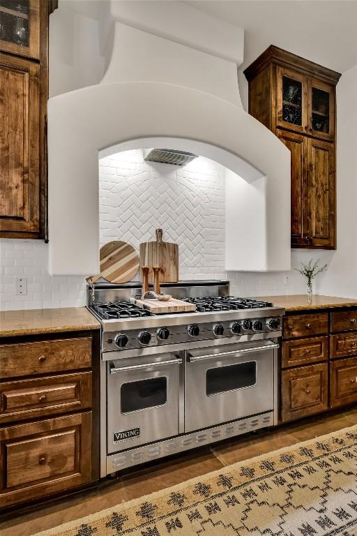 1710 Mount Larson Rd, Austin, TX 78746 - kitchen featuring double oven range, backsplash, light countertops, and glass insert cabinets